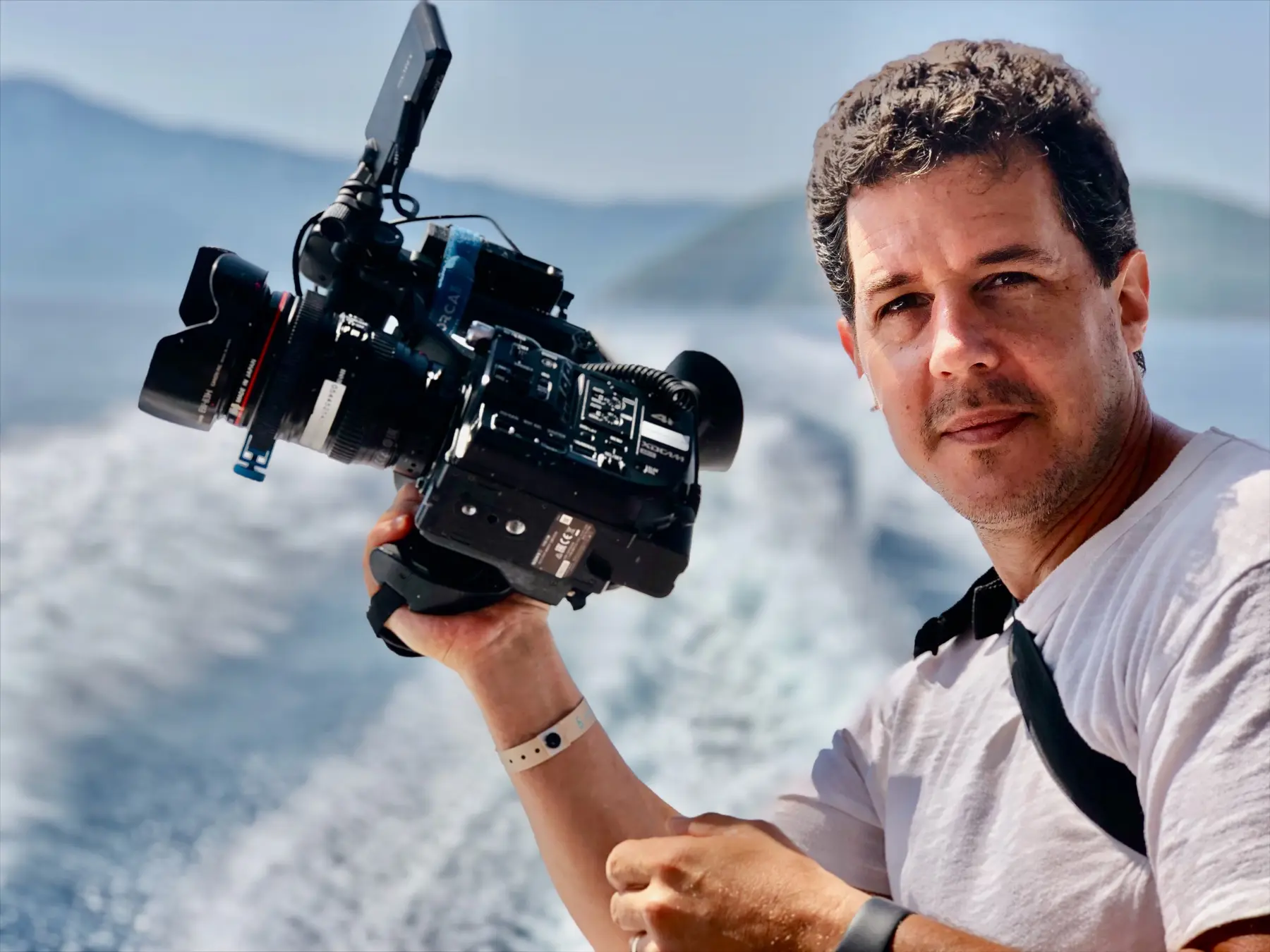 Itai Raziel holding a cinema camera on a boat at sea
